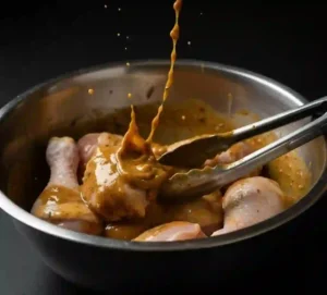 Pilons de Poulet au Four : La Recette Facile et Incontournable 6 Pilons enrobés de marinade dans grand bol, pince de cuisine, prêt à enfourner